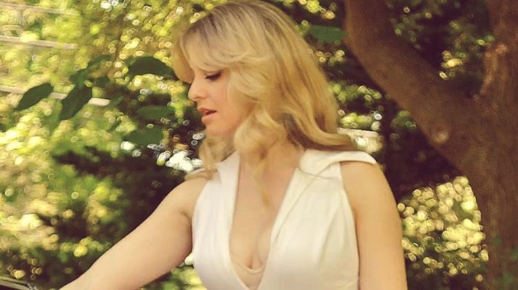 Soft film still in a white dress among sunlit leaves
