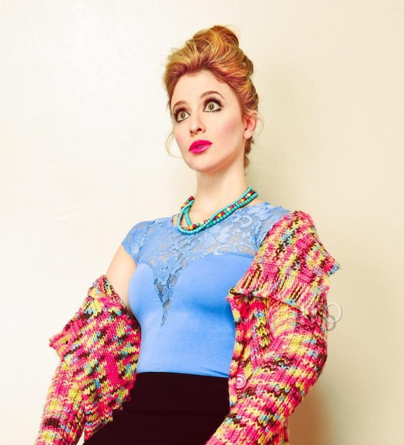 Comedic wide-eyed portrait in a pink knit and blue lace top