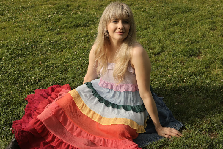 Seated on the grass in a rainbow ruffled dress